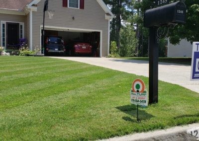 A house's garage surrounded by a green lawn.
