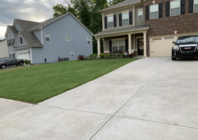 A parking zone in front of a traditional house with a green front yard.