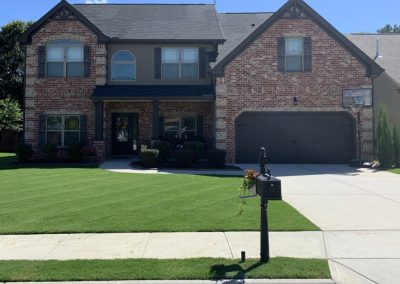 A beautiful brick house with a black roof and adorned with a carefully preserved front garden.