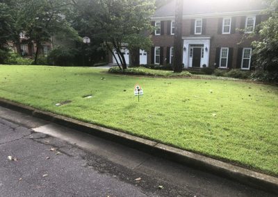 A huge traditional brown house with a manicured lawn.