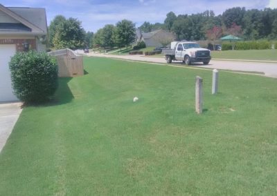 A pickup truck next to a front yard on a sunny day.