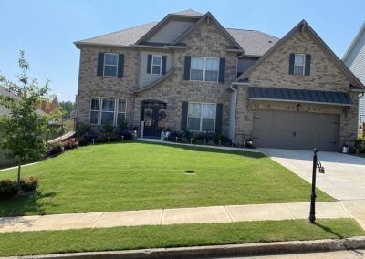 A yellow brick house with a healthy garden on a sunny day.