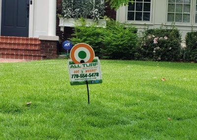 An All Turf sign in the middle of a front yard.
