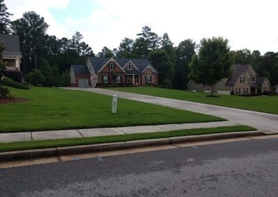 A classic exterior home design red brick house surrounded by green trees and lawns.