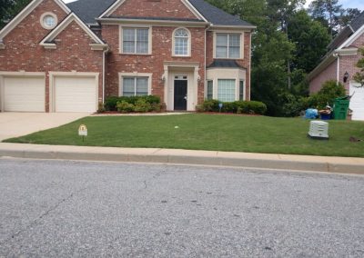 A red brick house with a healthy garden next to the street.