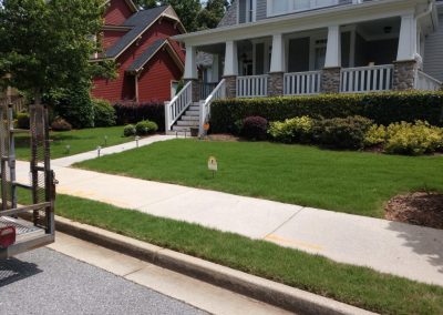 An impeccably maintained yard in front of a white-railed house.